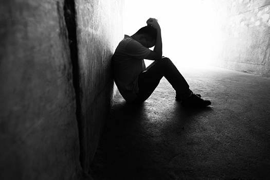 young man sits on the ground with his head in his hands