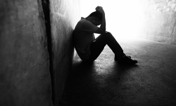 young man sits on the ground with his head in his hands